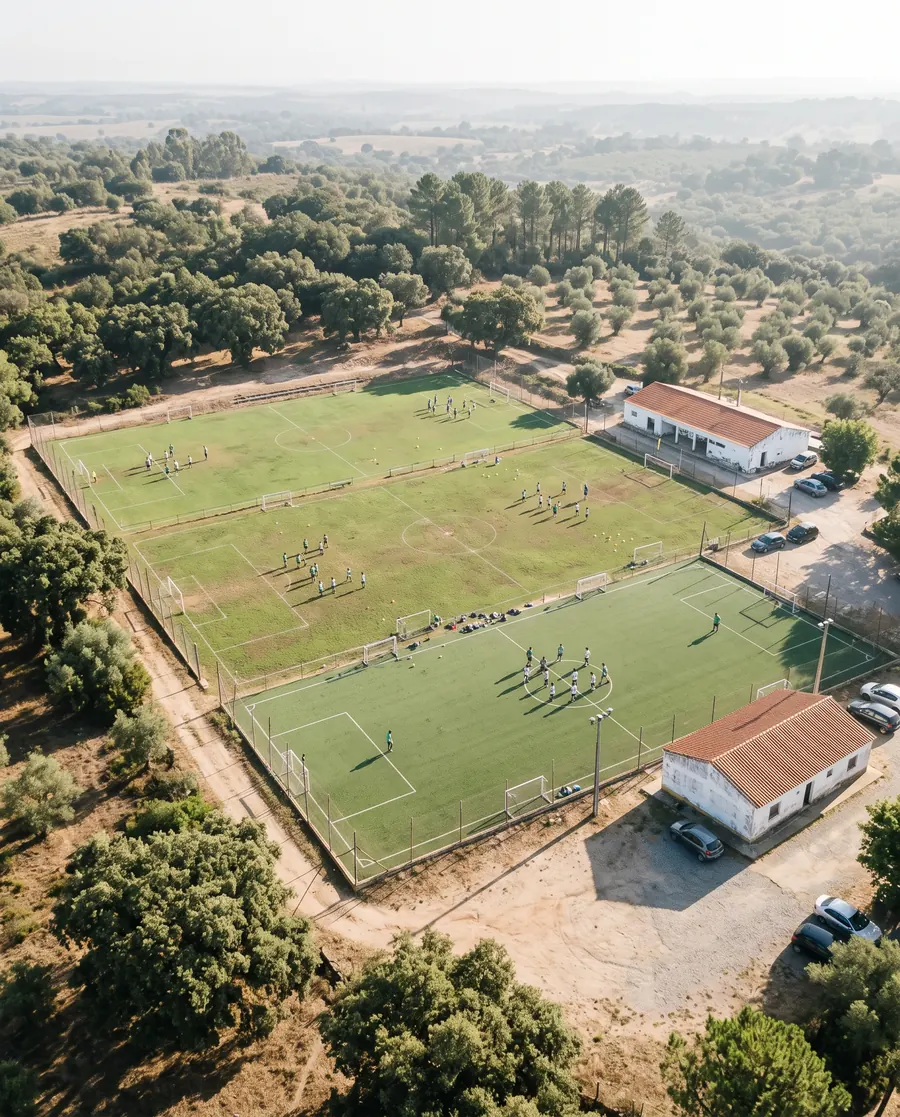 Um complexo desportivo de formação visto do alto, com vários campos e equipas a treinar